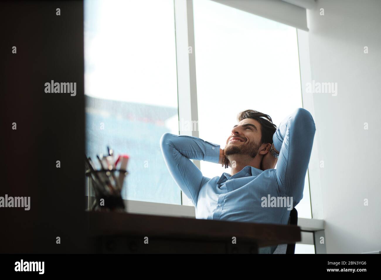 Happy Business Man With Hands Behind Head Leaning On Chair Stock Photo