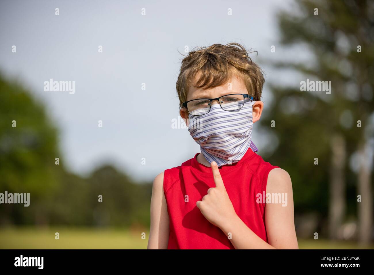 Child points to mask covering his face for protection during pandemic Stock Photo