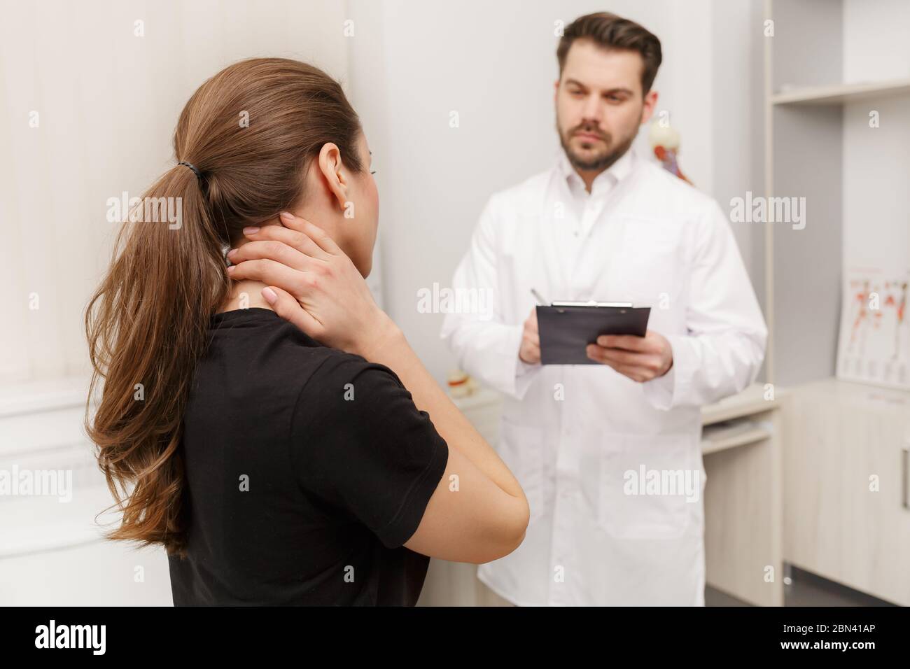 Male Doctor Examining Female Patient Suffering From Neck Pain Medical