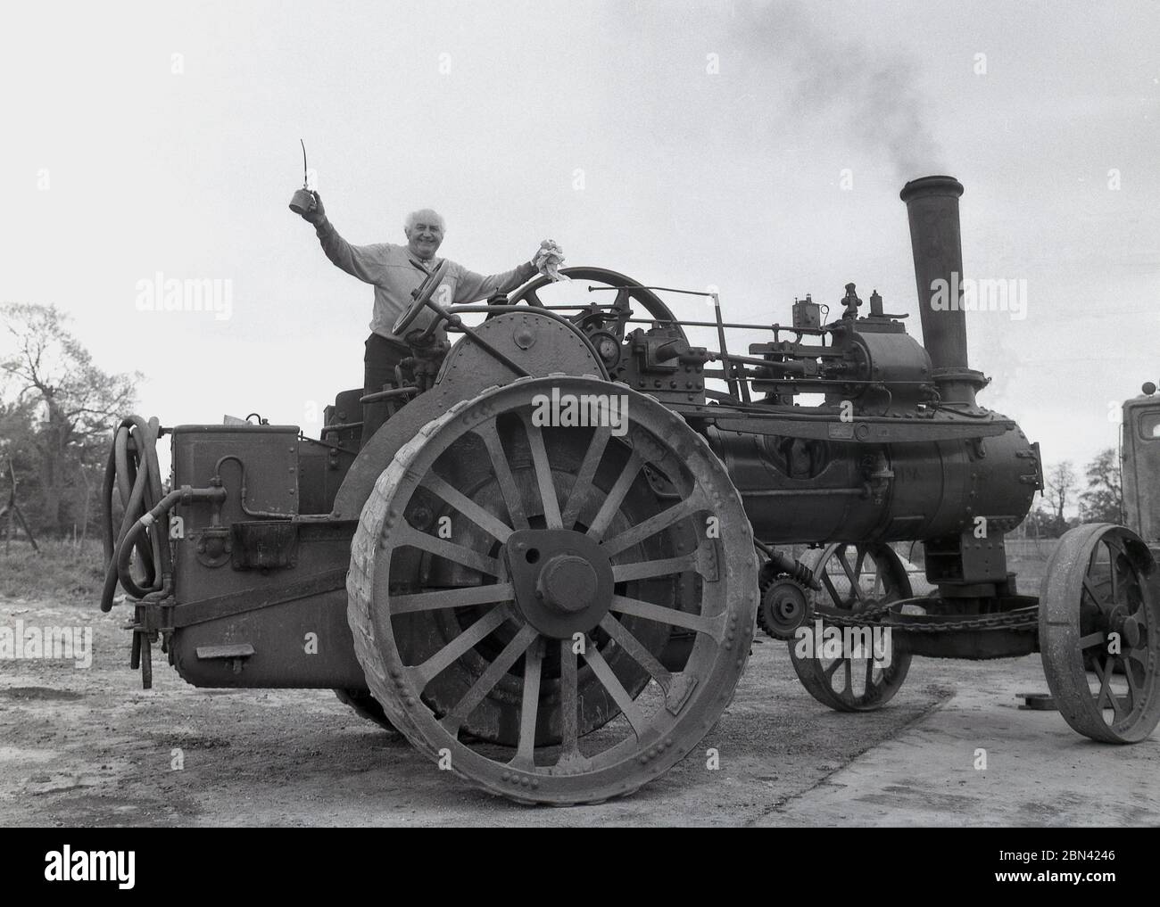 1980s, success!... a man standing on top of a large steam tractor