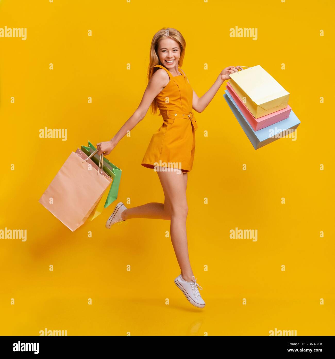 Seasonal Sales. Beautiful Shopaholic Young Girl Jumping With Shopping Bags In Hands Stock Photo