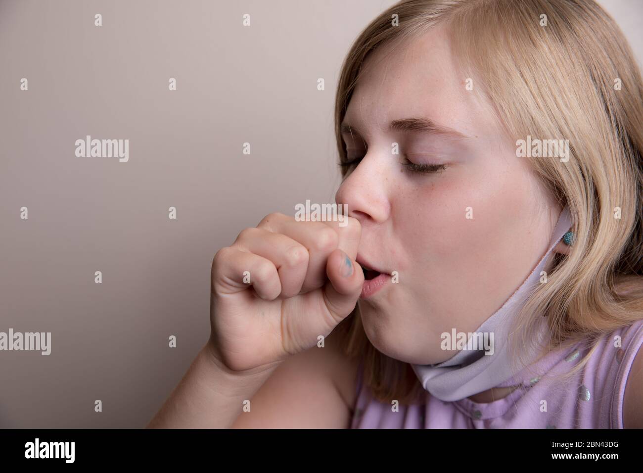 young girl uncovers her face to cough Stock Photo