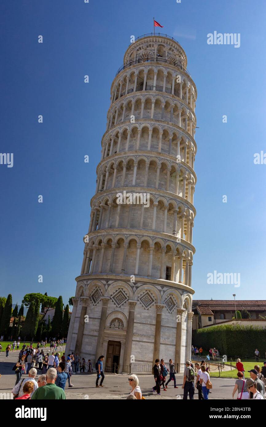 The Leaning Tower of Pisa rises up against a clear blue sky, surrounded by tourists, in Pisa, Italy Stock Photo