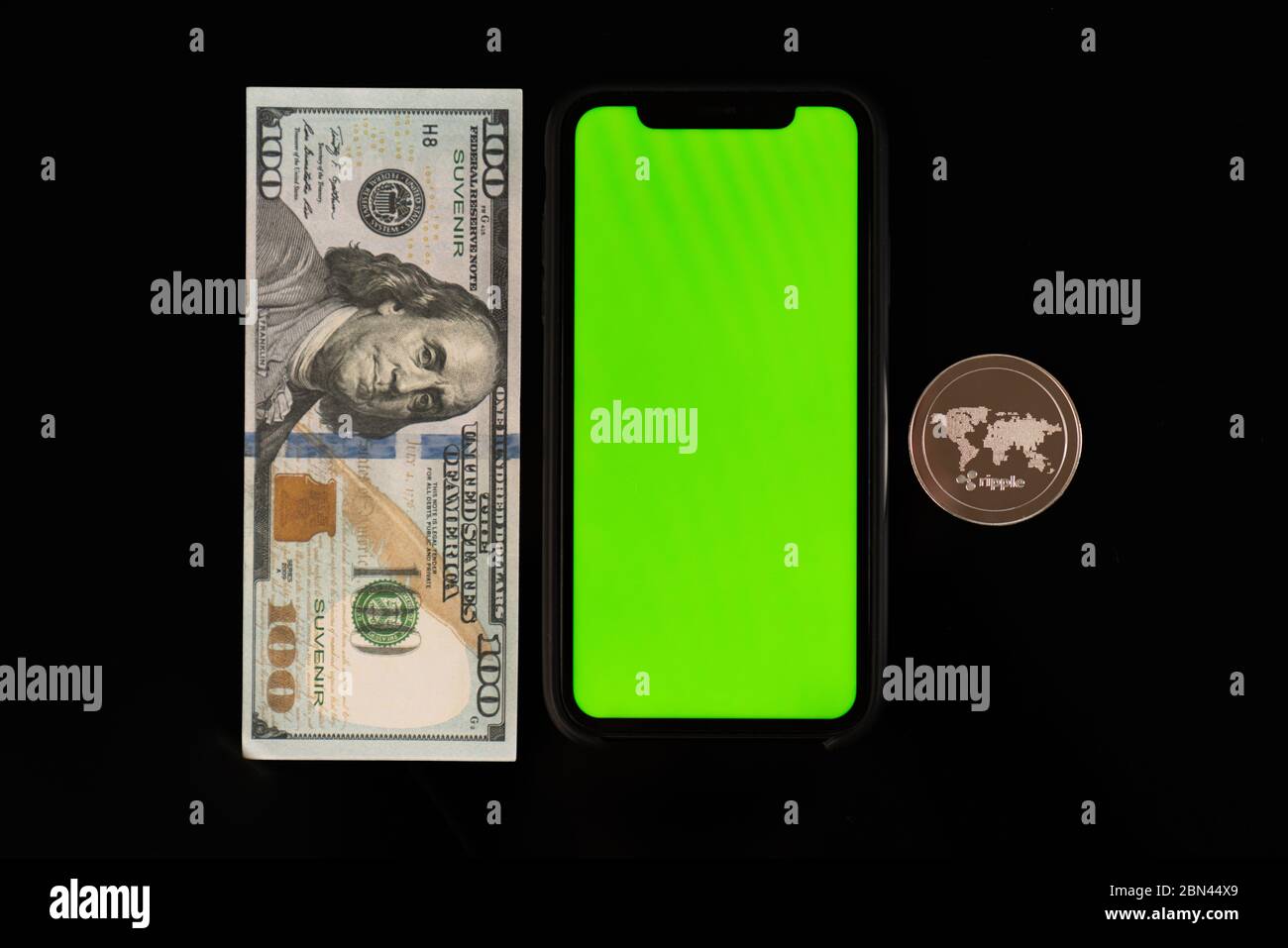 100 dollar banknote, phone with green screen and ripple coin isolated on black background Stock Photo