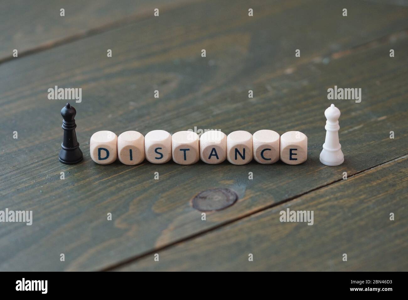 Cube with 'DISTANCE' text and miniature People figures. Conceptual image about social distancing, mandatory due to the coronavirus outbreak, Covid-19. Stock Photo