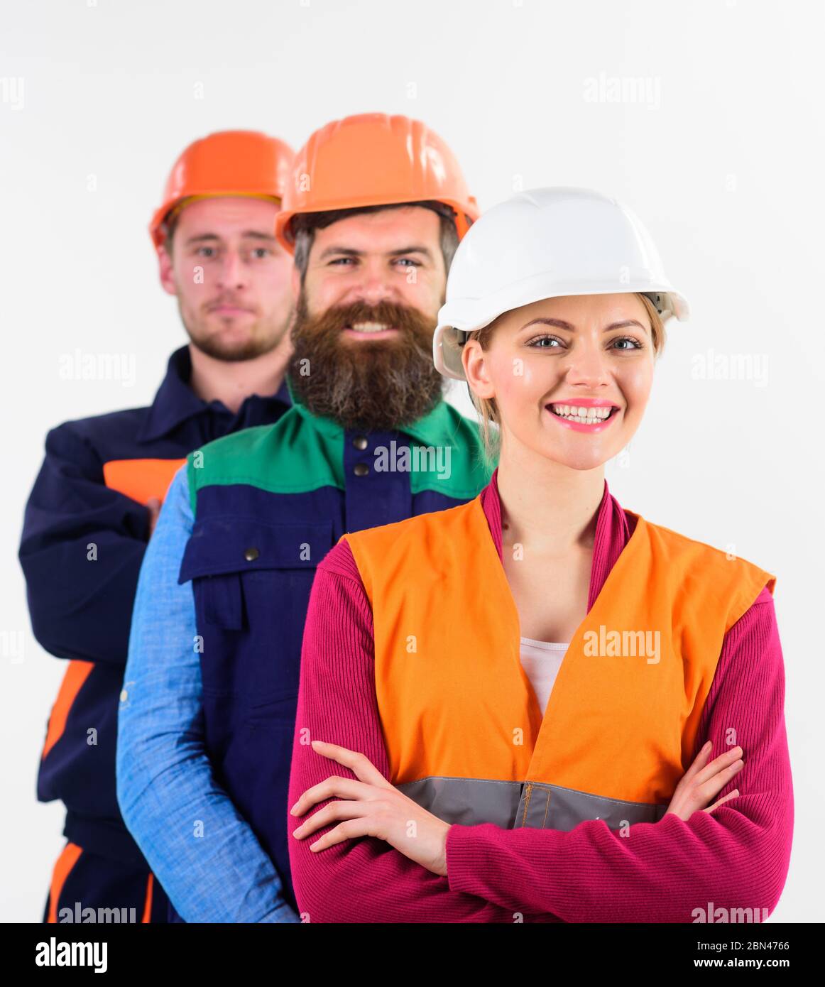 Woman and men in hard hats stand close as team. Team of architects ...