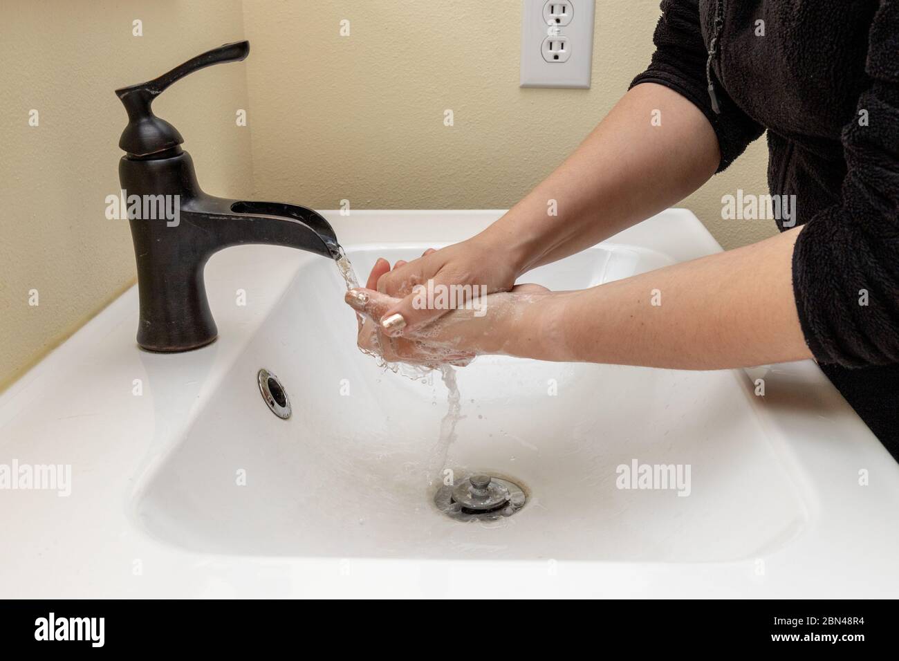 Female Washing Hands with Soapy Water to Protect Against Germs Stock Photo