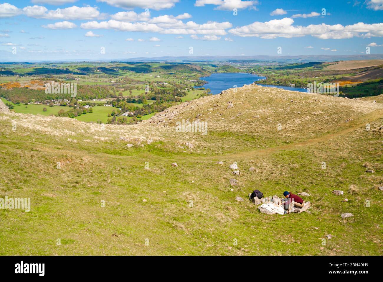 Female hiker stops for lunch abve Ullswater. The Lake District National park, Cumblria, England. UK Stock Photo