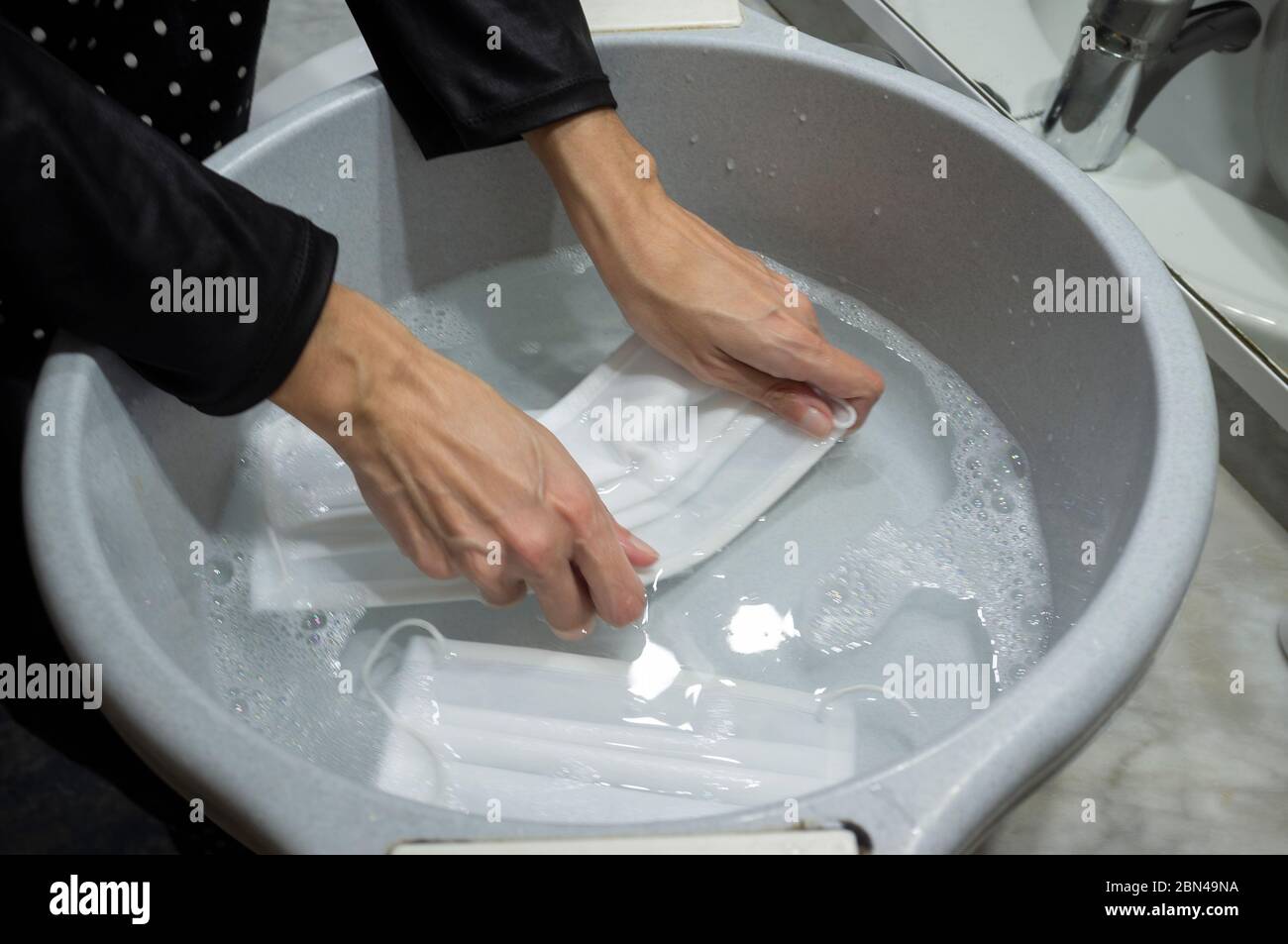 Girl wahsing face masks in big bowl Stock Photo