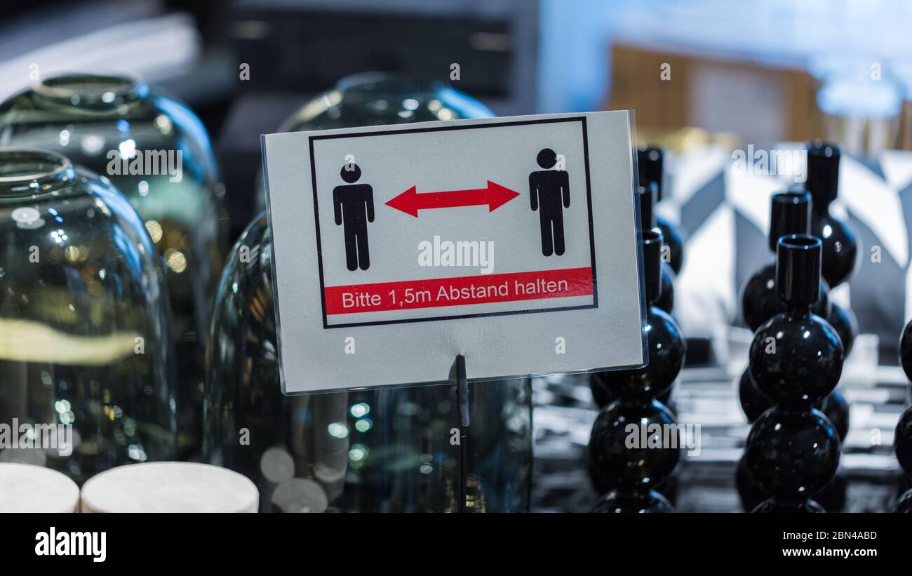 Keep distance sign inside a H&M Home store in the pedestrian zone. Homeware in the background. Stock Photo