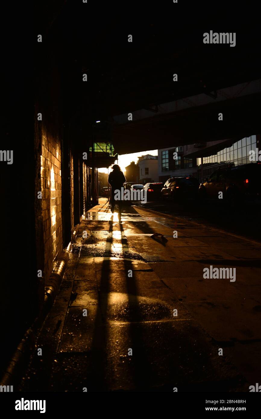An anonymous person  casts a shadow at sundown beneath a bridge Stock Photo