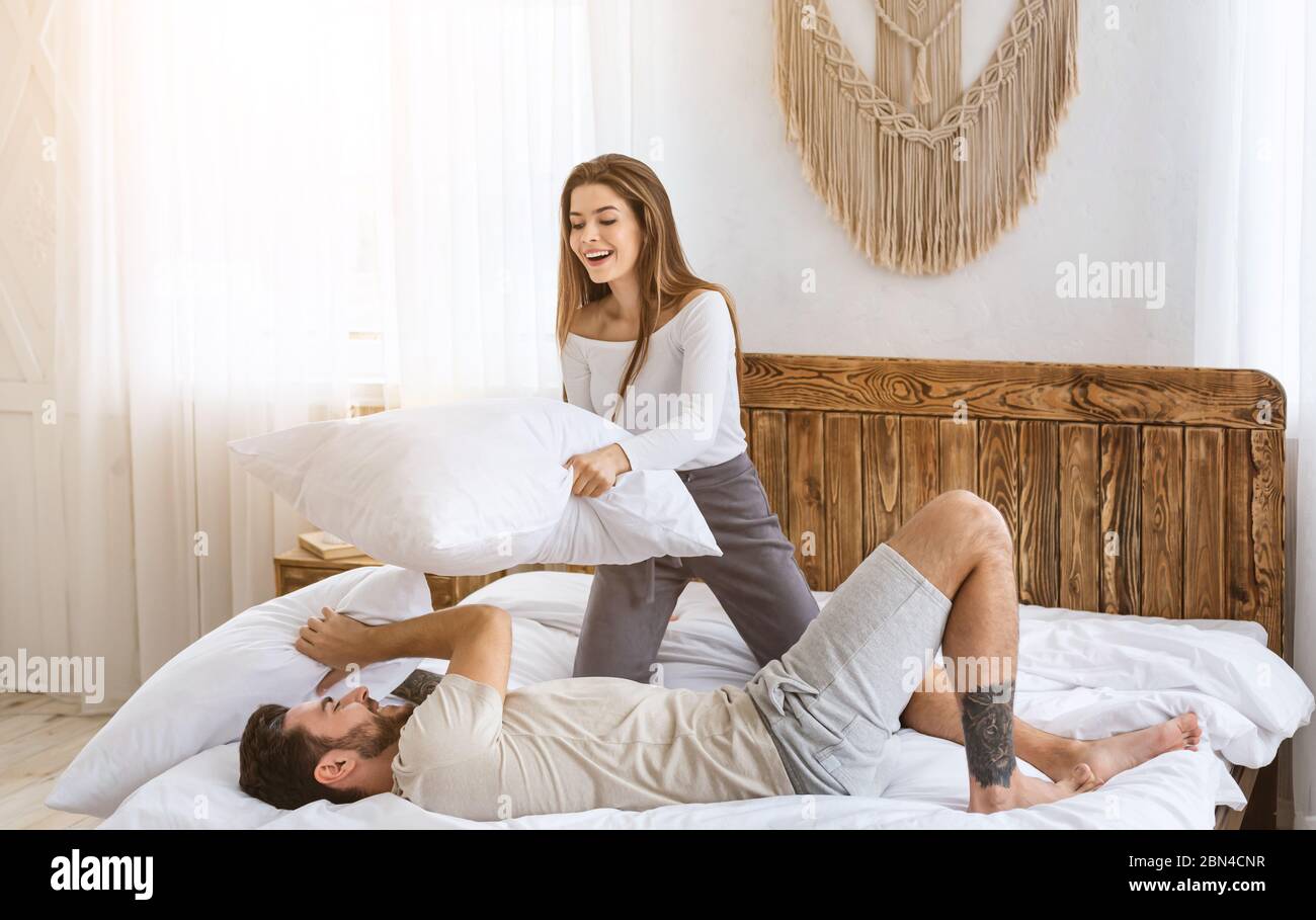 Home alone concept. Happy couple fights pillows, girl defeats guy Stock Photo