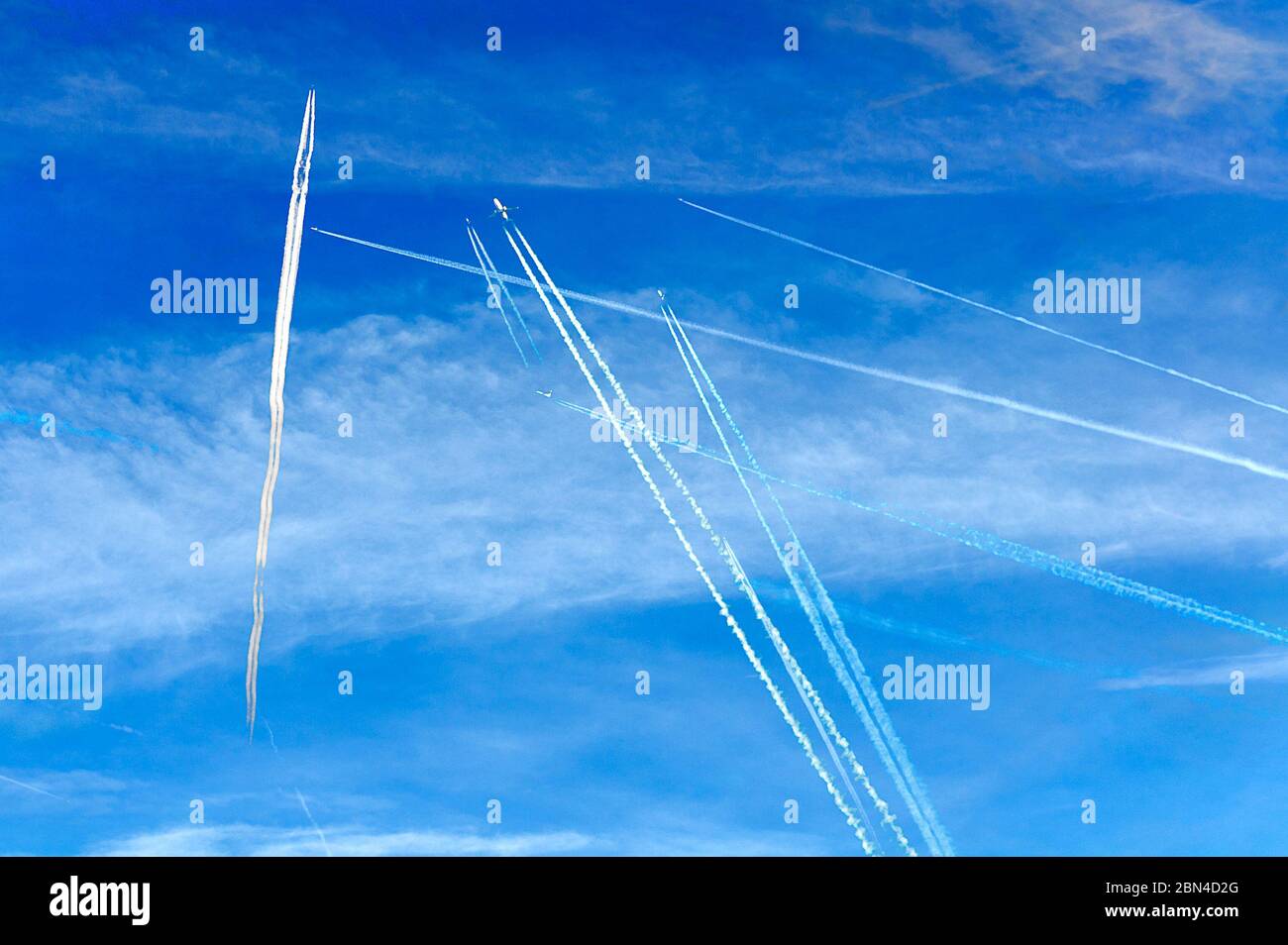 some crossing condensation trails of airplanes on the blue sky Stock Photo