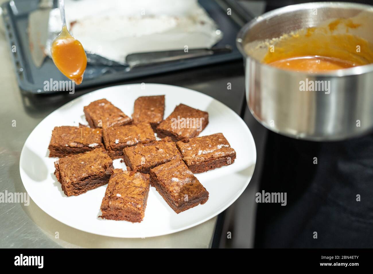 Brownie pieces being poured with salted caramel sauce Stock Photo