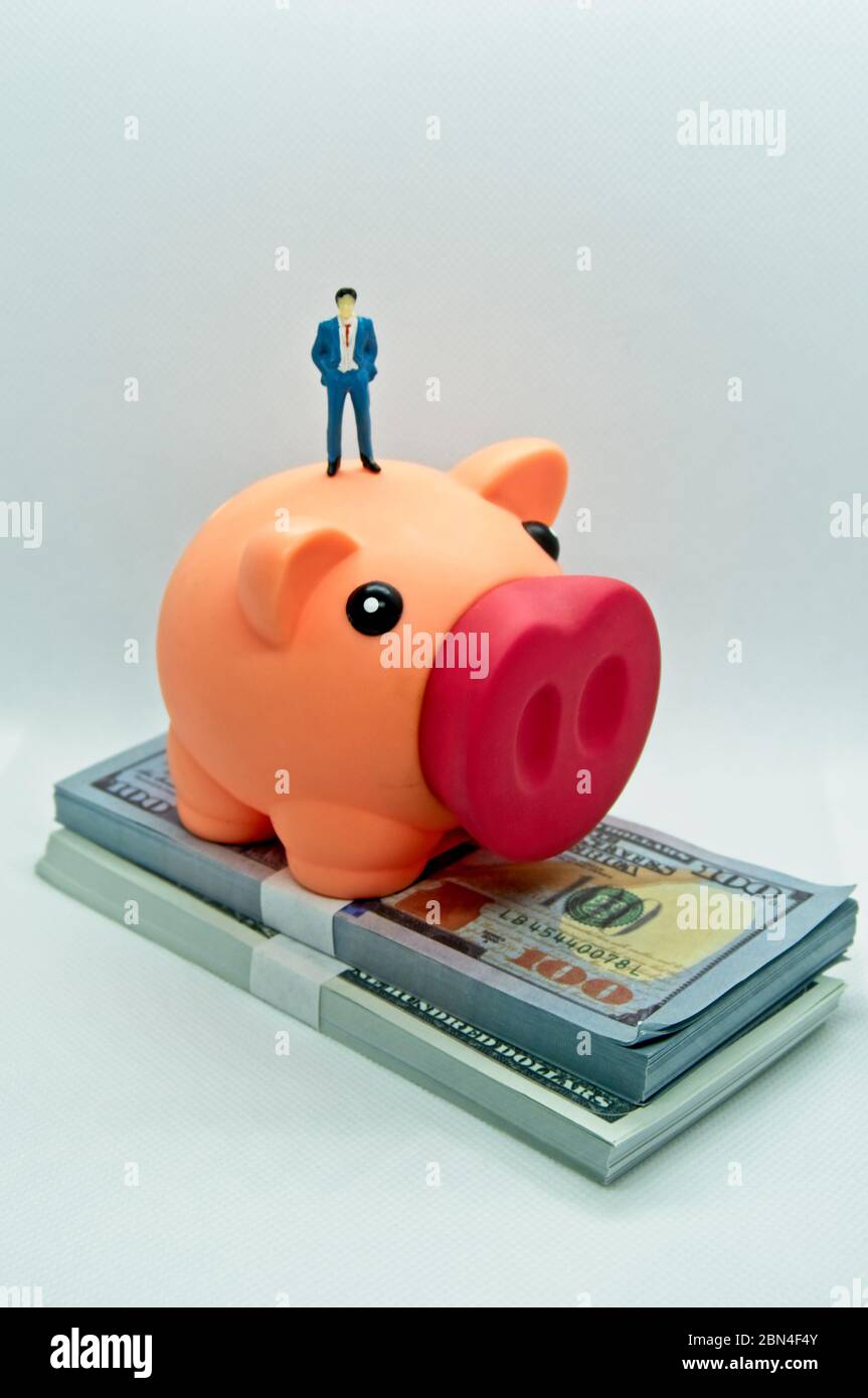 Piggy bank with a figure of a man in a suit standing on top it and on ...