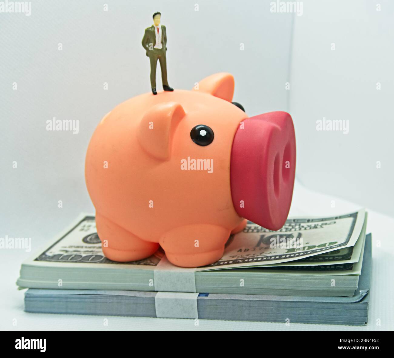 Piggy bank with a figure of a man in a suit standing on top it and on ...