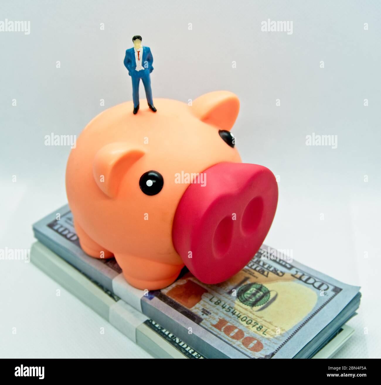 Piggy bank with a figure of a man in a suit standing on top it and on ...
