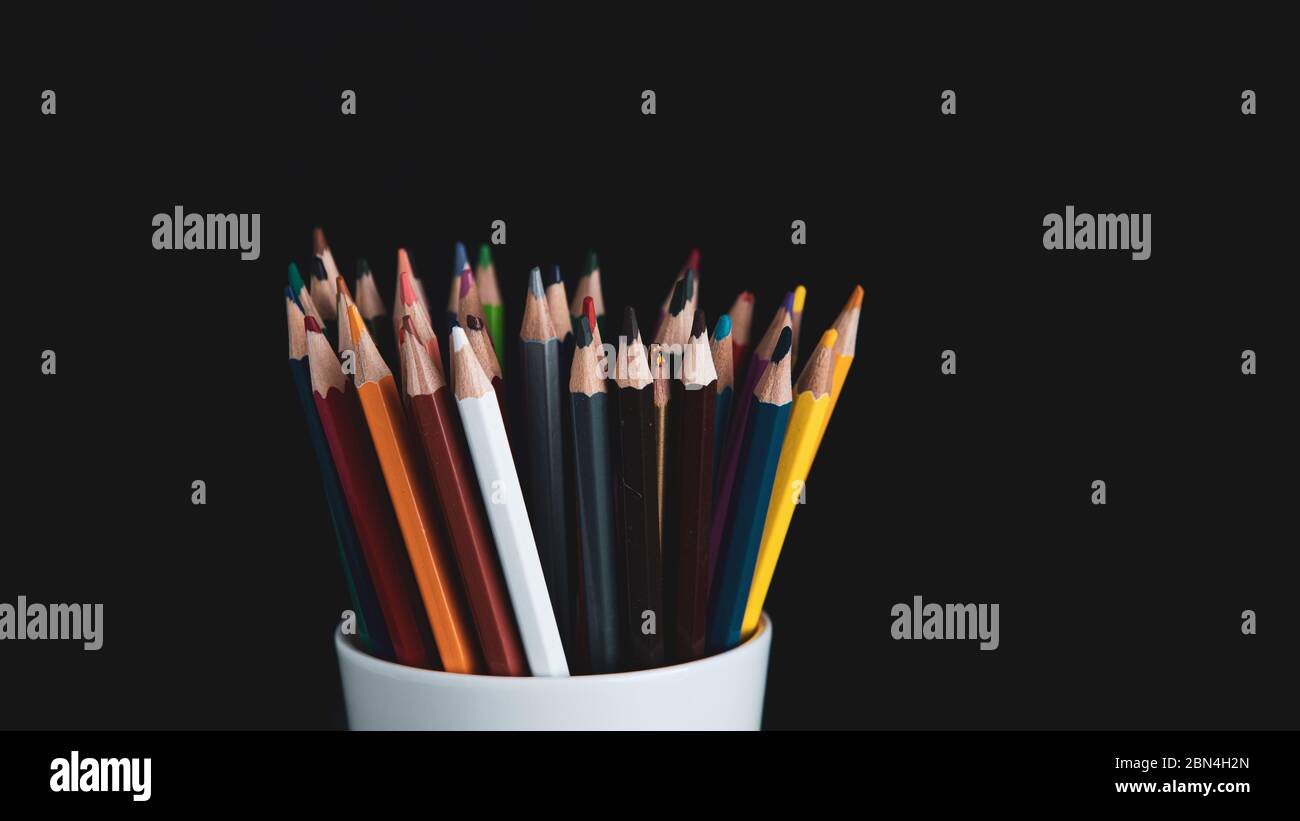 colored pencils in white cup on a black background Stock Photo