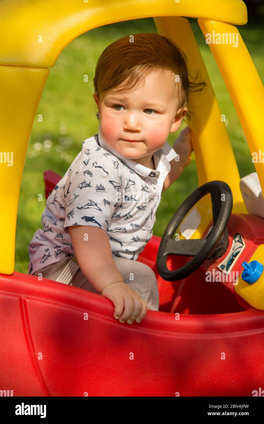 young boy in a plastic toy car Stock Photo