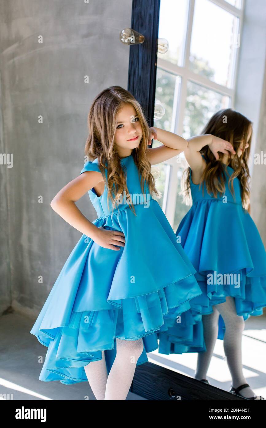 The lovely little girl posing in a beautiful blue dress is posing ...