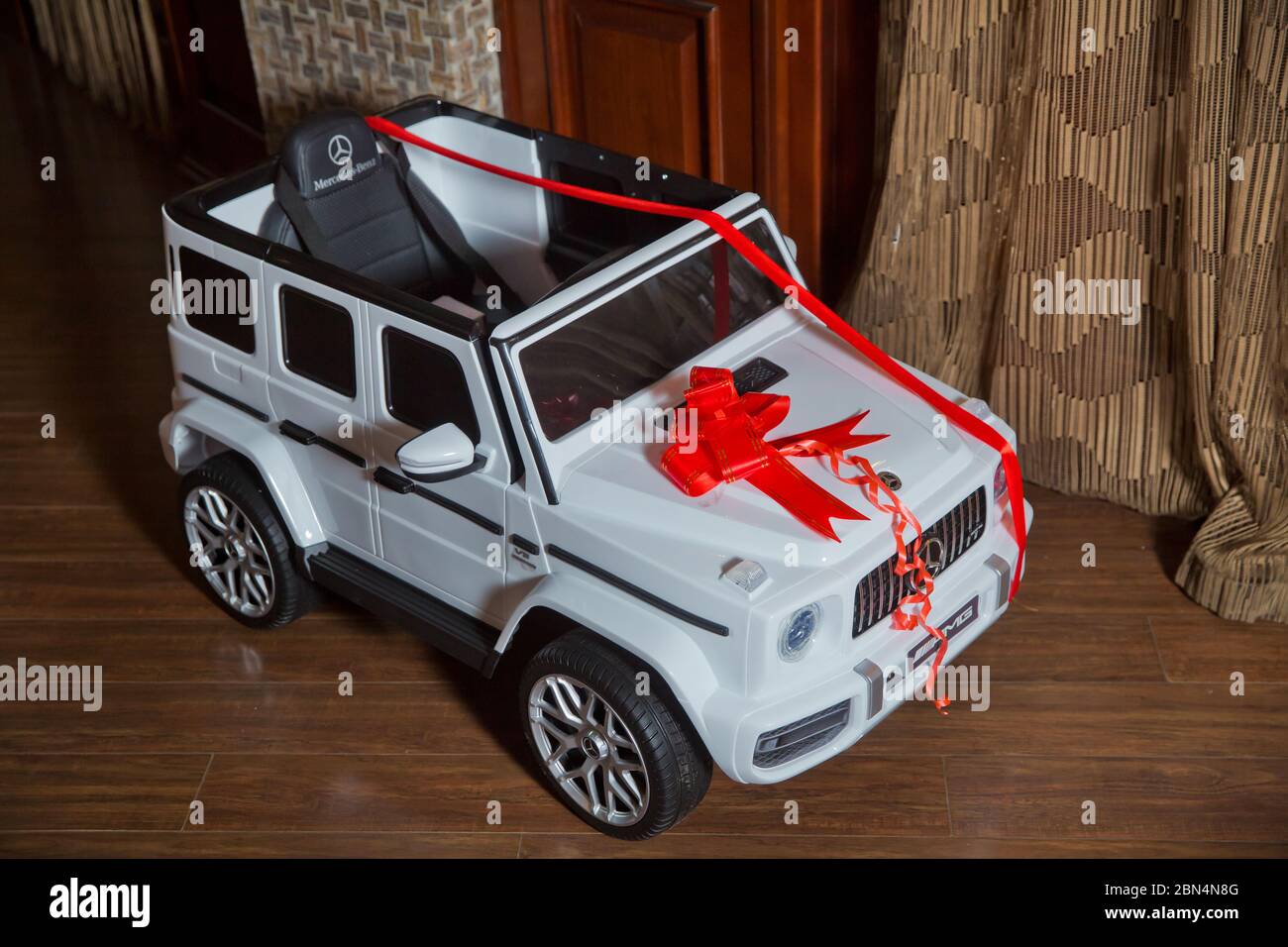 Monsterous white Mercedes G63 AMG toy cars . A tape is tied around the child's car. Birthday gift baby car . Azerbaycan Baku 28.12.2019. Stock Photo