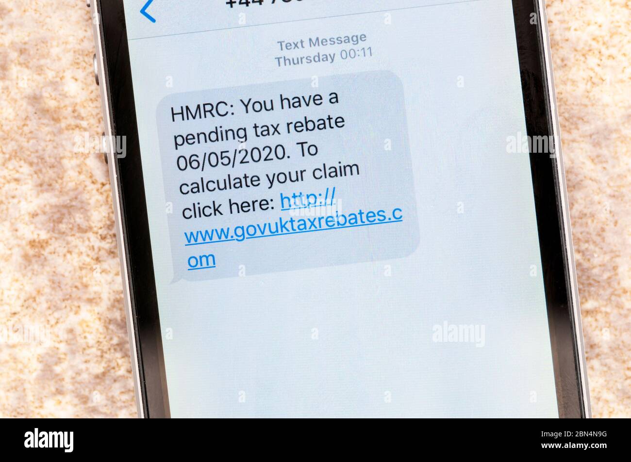 A scam message displayed on an iphone that pretends to be from HMRC with a pending tax rebate. Stock Photo