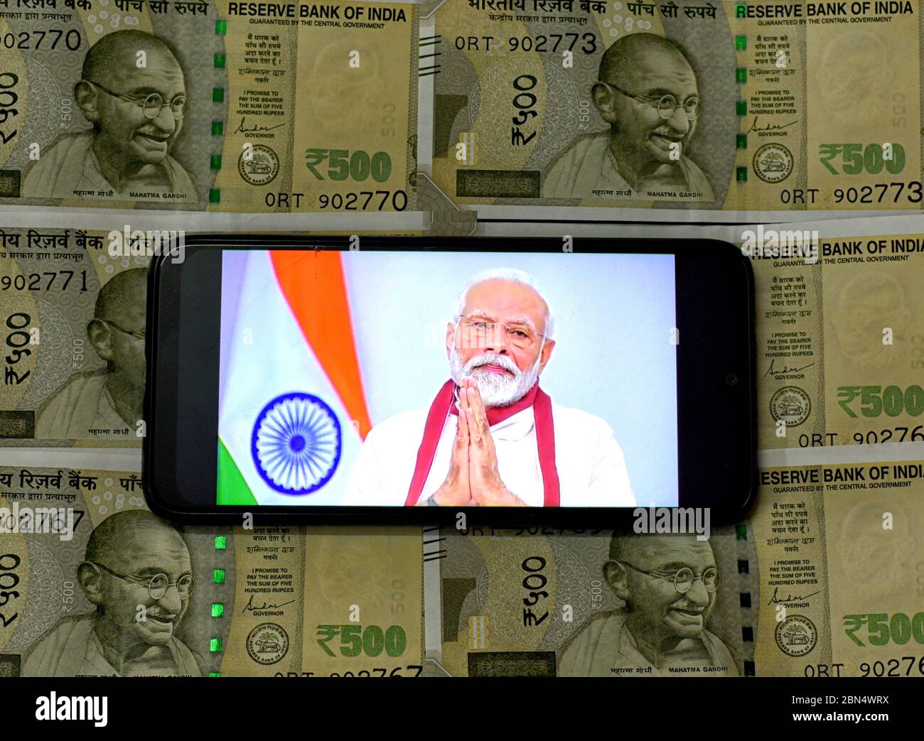 In this photo illustration Indian Prime Minister, Narendra Modi speaking to  the Nation about Covid19 crisis on a smartphone with a background of the  Indian Currency  Minister, Narendra Modi has announced