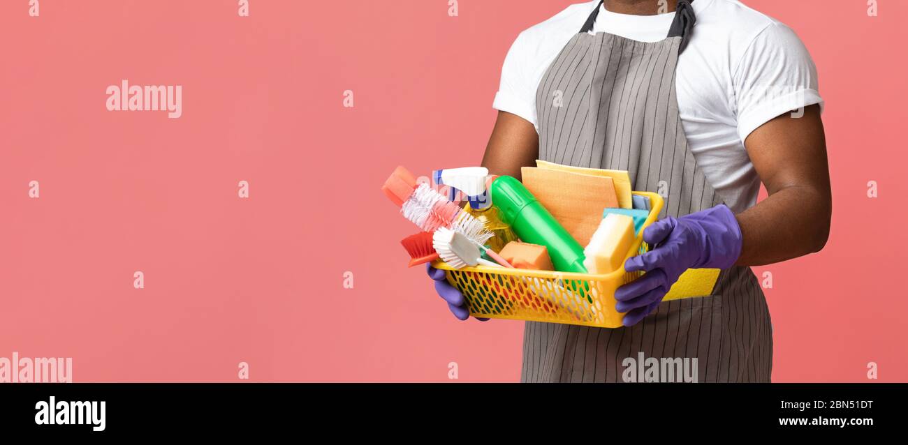 Cleaning supplies in basket in hands of unrecognizable black male janitor Stock Photo