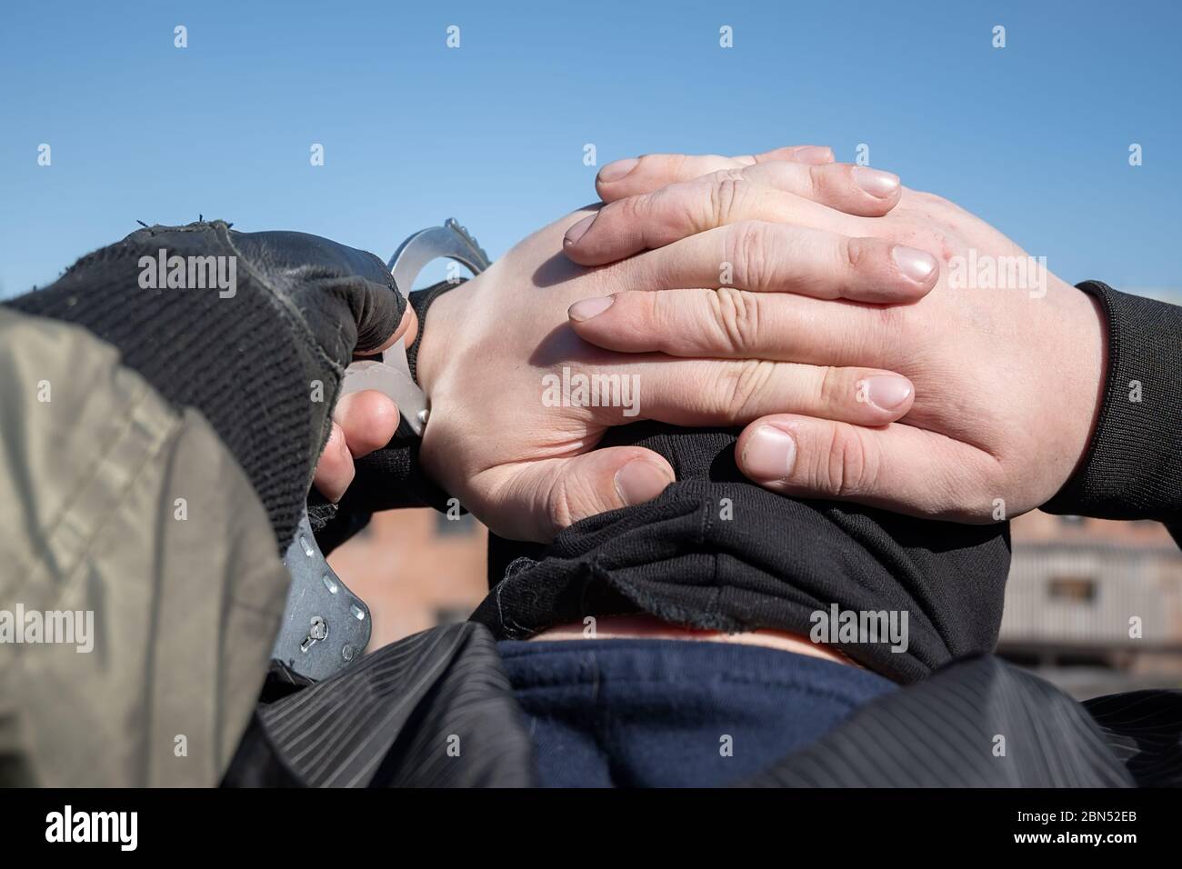 arrest of a criminal, a police officer puts handcuffs on the hands of a bandit Stock Photo