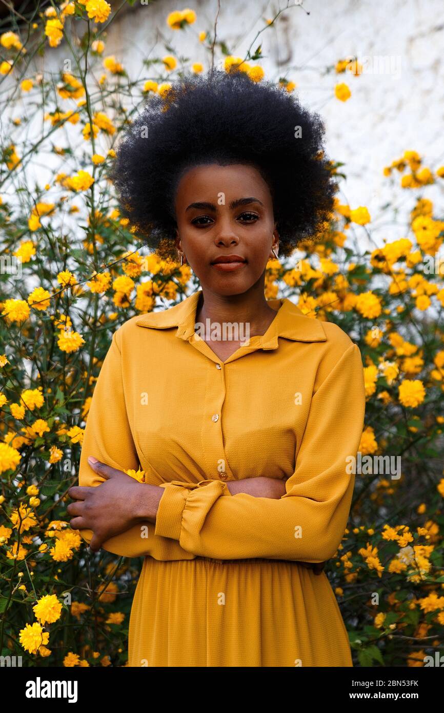 young african american woman in yellow dress enjoying a garden with ...