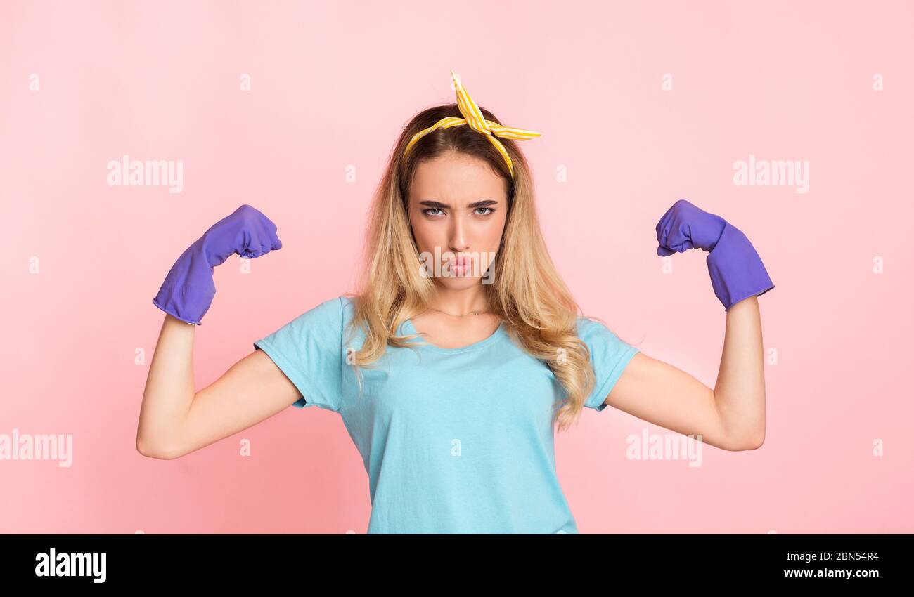 Victory over mud concept. Housewife in rubber gloves, blowing lips, shows biceps Stock Photo