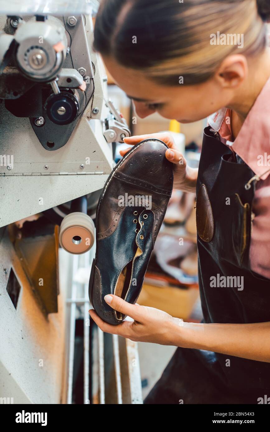 Woman cobbler working on machine in her shoemaker workshop Stock Photo