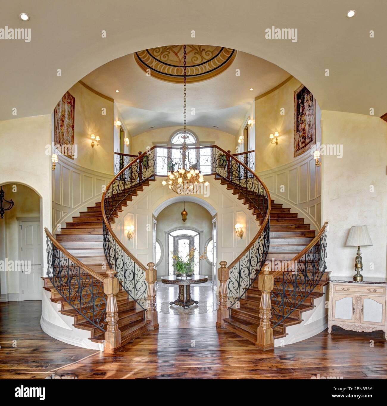 The grand staircase with walnut stair treads, newell posts and banisetrs in an upscale custon build home. Stock Photo