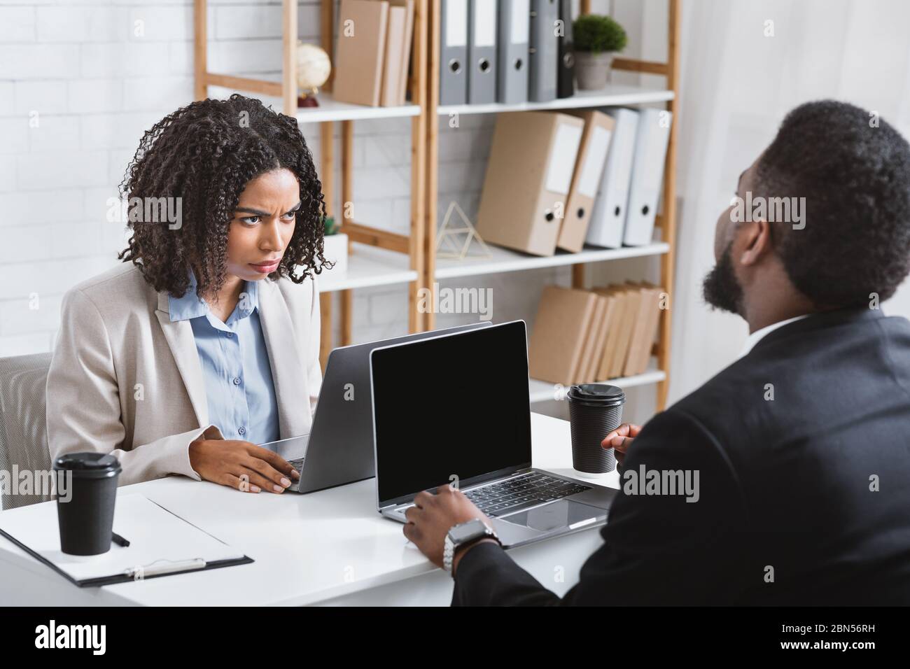 Annoyed African American woman having disagreement with her colleague at workplace, copy space Stock Photo
