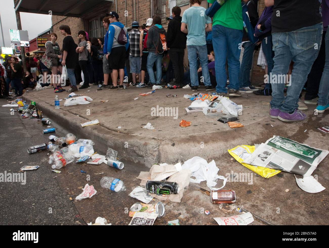Austin Texas USA, March 2012: Garbage piles up in the street and on the sidewalk as young music fans stand in line outside a music venue waiting to hear bands during the South by Southwest Music Conference. ©Marjorie Kamys Cotera/Daemmrich Photography Stock Photo