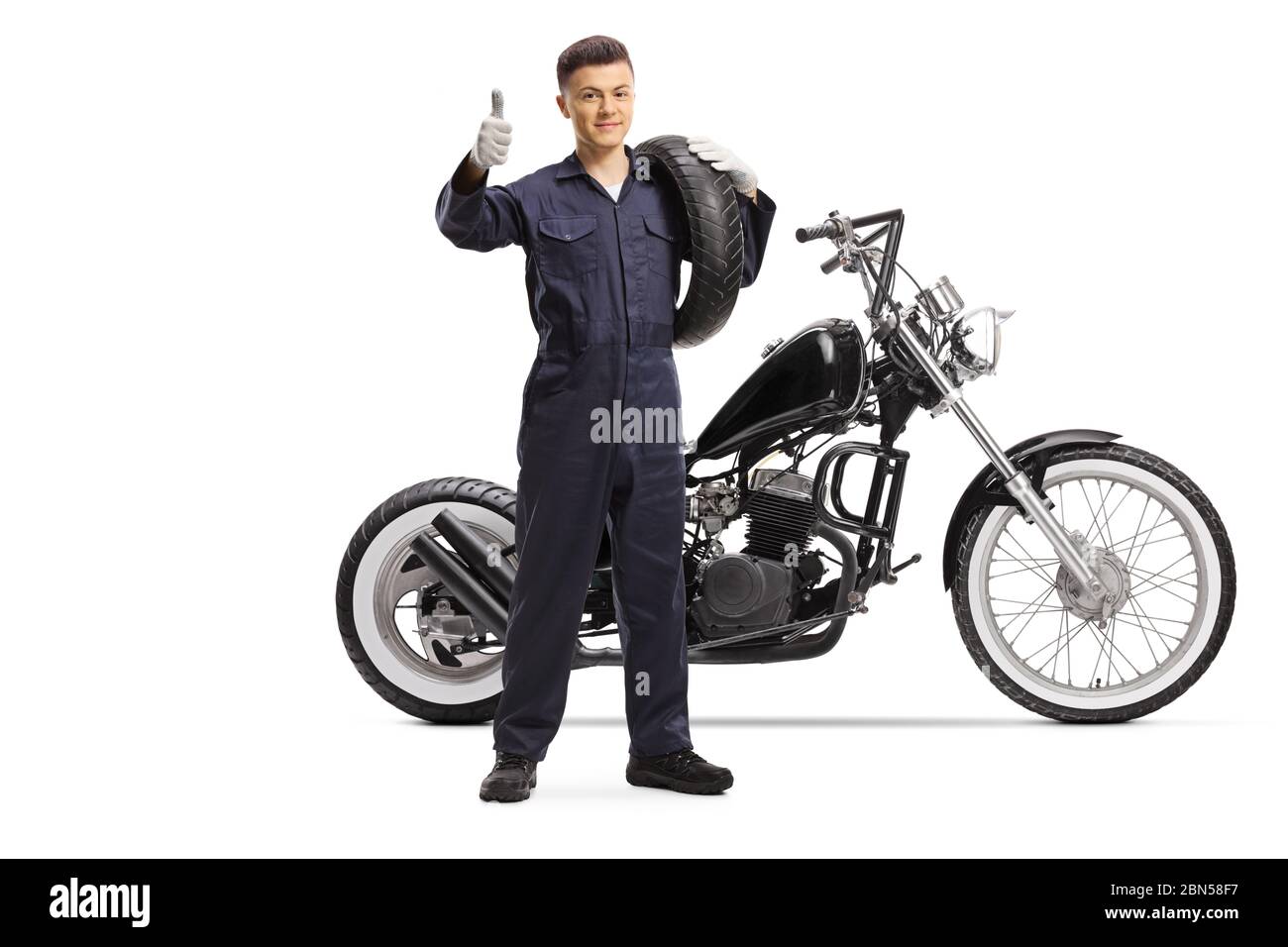 Full length portrait of a mechanic with a chopper carrying a motorbike ...