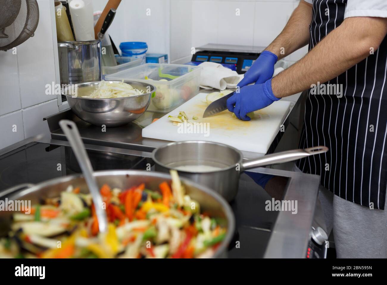 Unrecognizable man slicing apples while cooking fresh vegetables Stock Photo