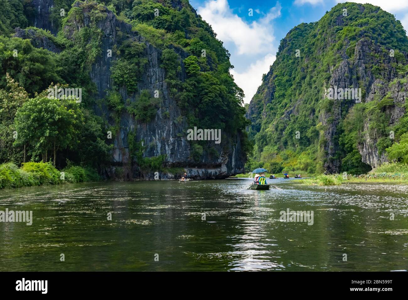 Tourists in a boat exploring the scenery Ngo Dong River. Beautiful scenery, cliffs and river. Ninh Binh province, Vietnam Stock Photo