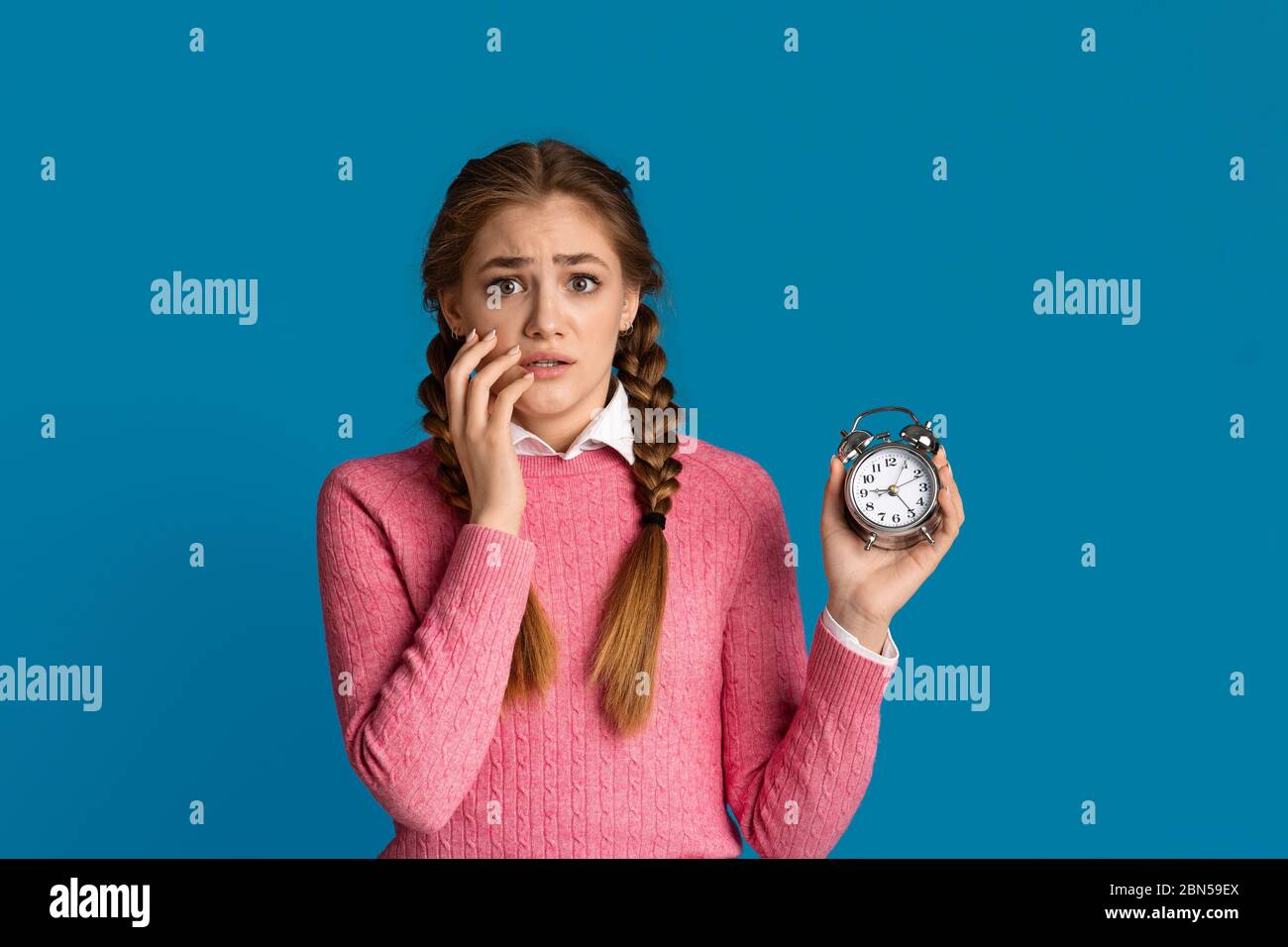 Shocked girl with alarm clock in hand Stock Photo