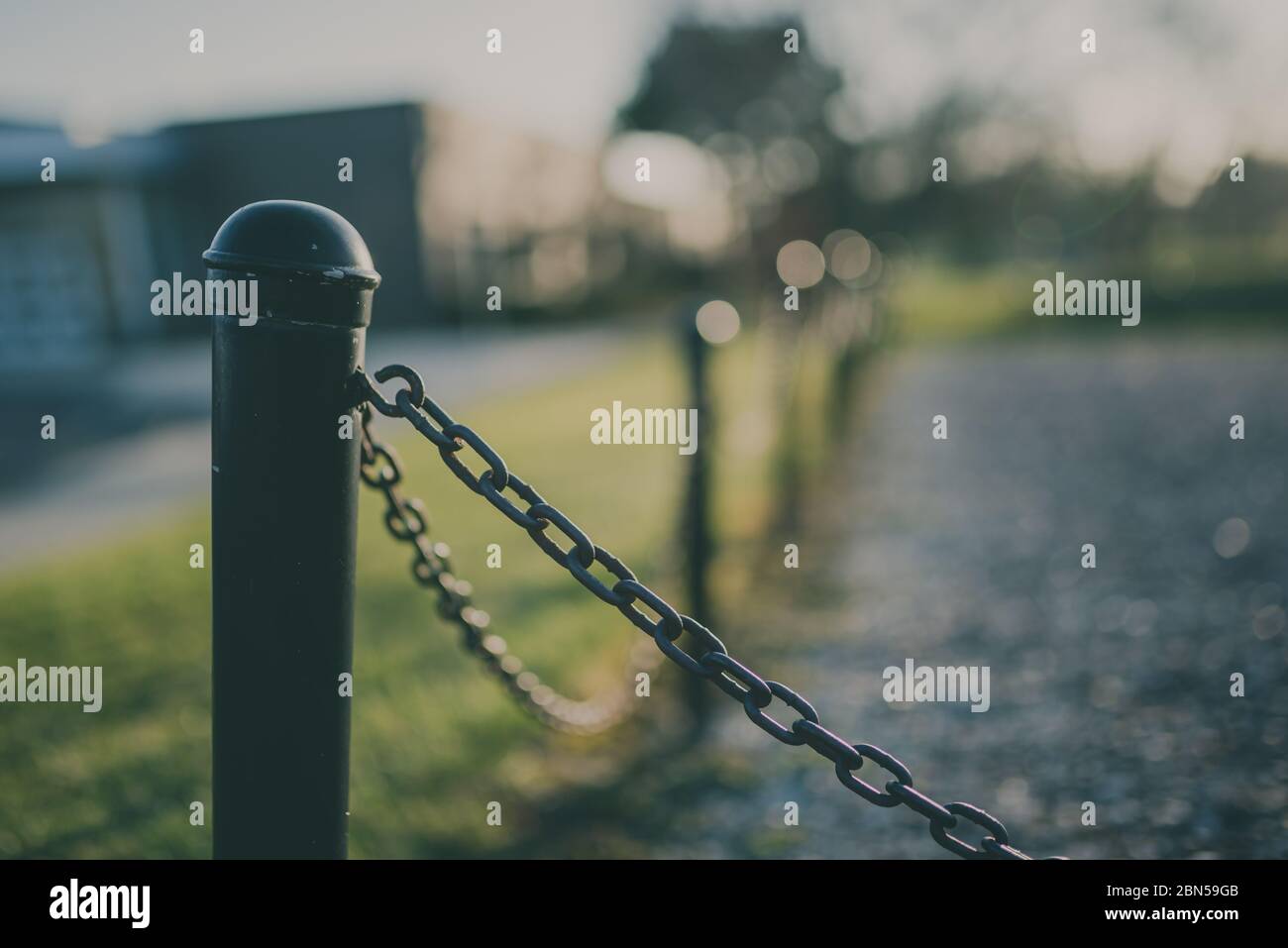 Black fence with chains and pillars with intentional blurred background Stock Photo