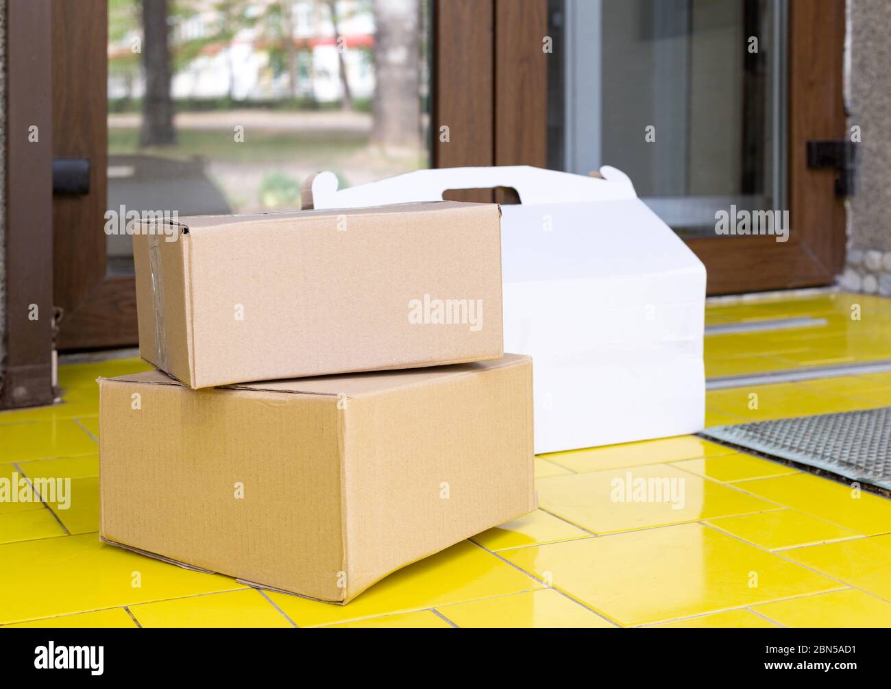 Delivery boxes on doorstep at home. Contactless food delivery. Safe shopping E-commerce purchase parcels at home. Boxes delivered to front door by Stock Photo