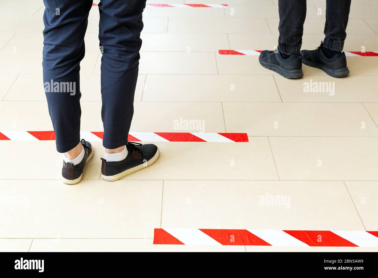 People stand in line keeping social distance, standing behind a warning line during covid 19 coronavirus quarantine. Safe shopping, Social distancing Stock Photo