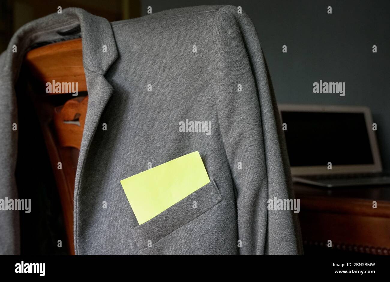 Blank yellow paper stuck out from pocket of a grey jacket. Space for text. Stock Photo