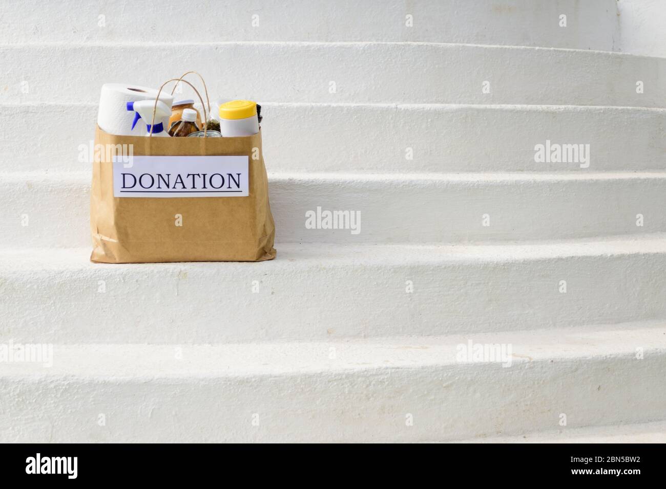 A donation bag filled with food and cleaning supplies sits on white steps while being delivered during the Covid-19 / Coronavirus Pandemic Stock Photo