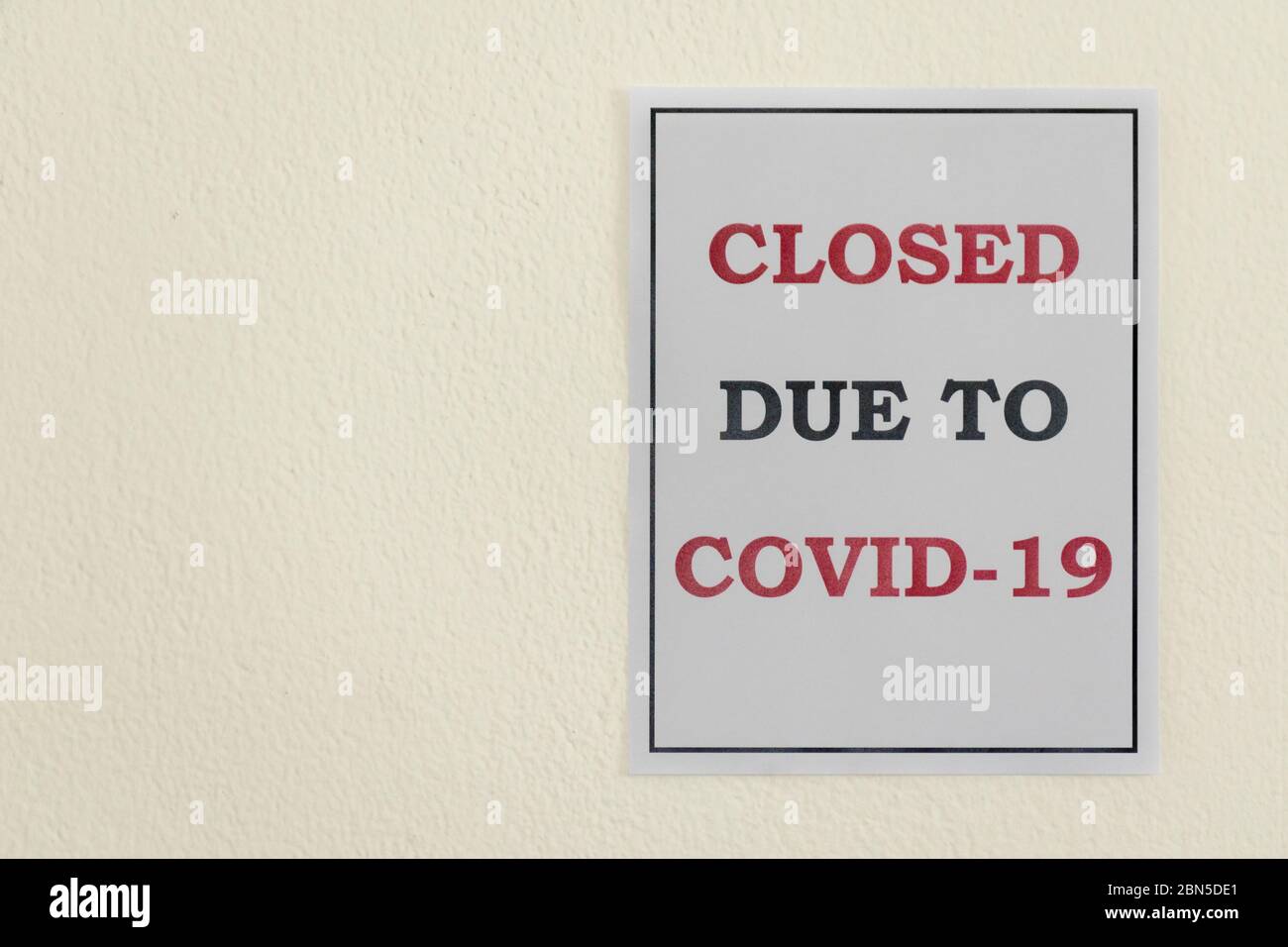 A 'Closed due to Covid-19' sign hangs on a wall during the Coronavirus Pandemic Stock Photo
