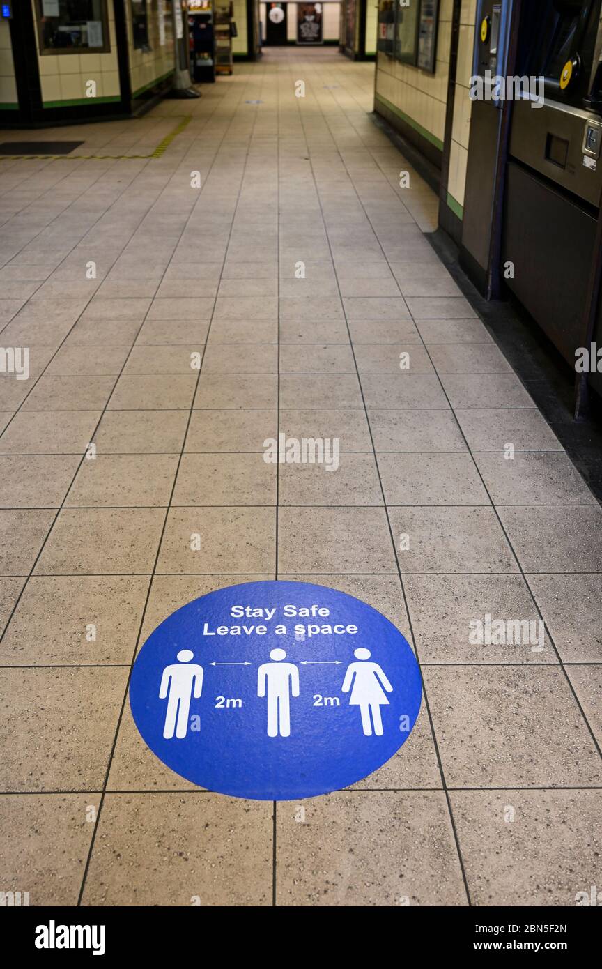 Notice on the floor of a tube station with the 2 meter distance for social distancing, in front of a narrowing corridor, during the covid-19 pandemic. Stock Photo