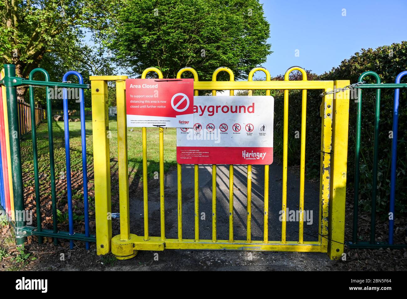 The locked gate of a playground or play park with a notice warning that it is closed because of the coronavirus pandemic. Stock Photo