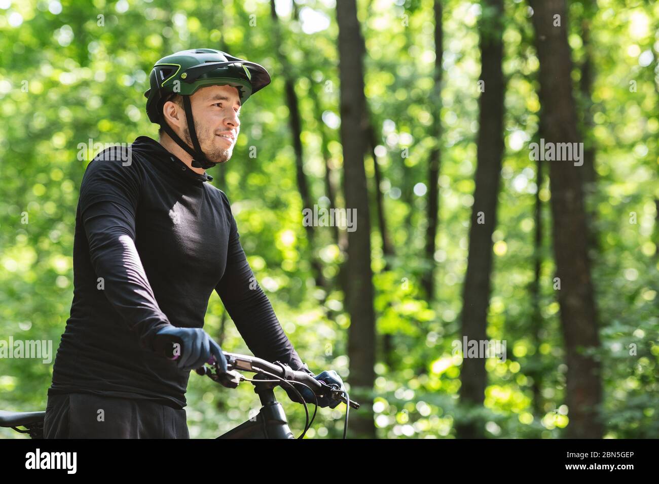 Young man cyclist enjoying riding in summer forest Stock Photo