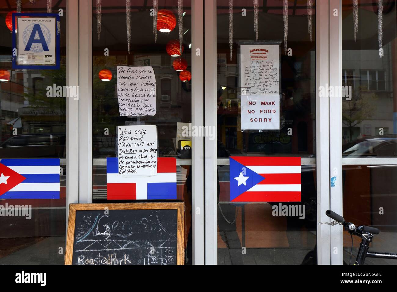 Coronavirus, social distancing and open for business signs in the window of Gena's Grill, a restaurant in New York's East Village during coronavirus Stock Photo