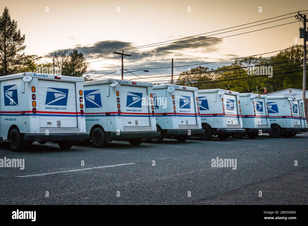A number parked United States Postal Services vans in front of a Post Office Stock Photo